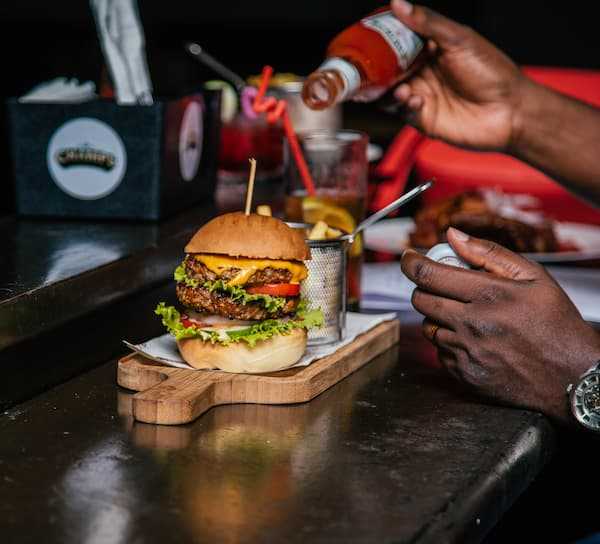 An influencer pours ketchup over a burger in a restaurant bar